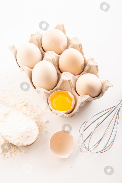 Скачать свежие куриные яйца с мукой на белом фоне. приготовление еды фотосток Ozero