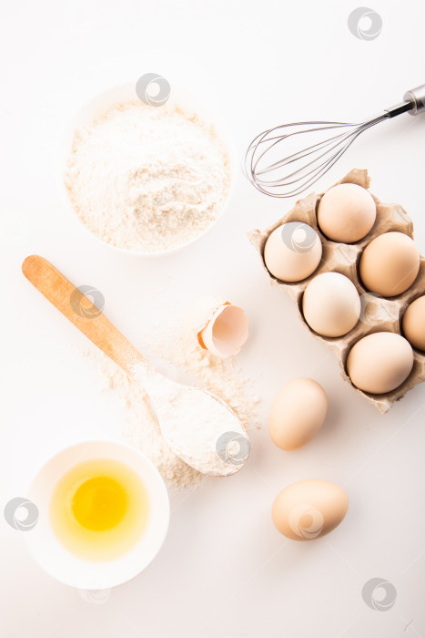 Скачать свежие куриные яйца с мукой на белом фоне. приготовление еды фотосток Ozero