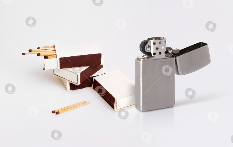 Скачать Несколько ретро-коробков спичек и металлическая газовая зажигалка выделяются на белом фоне фотосток Ozero