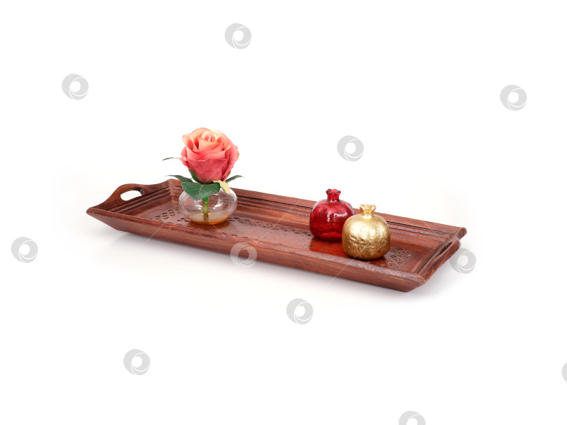 Скачать Деревянный резной декоративный поднос ручной работы на белом фоне. На подносе изображен натюрморт с вазой и розой и двумя маленькими стеклянными вазочками фотосток Ozero