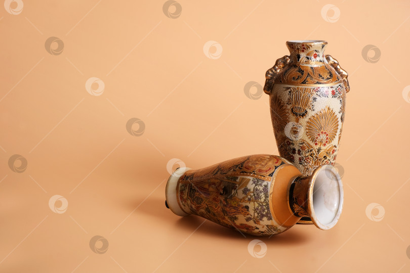 Скачать Две китайские вазы в старинных традициях, выделяющиеся на оранжевом фоне фотосток Ozero