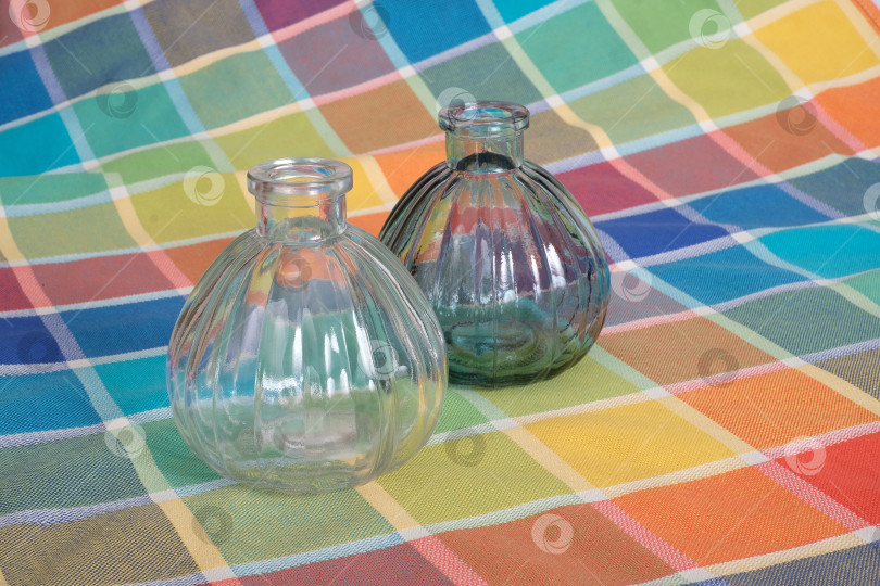 Скачать На яркой клетчатой скатерти стоят две стеклянные бутылки с ребристой текстурой фотосток Ozero
