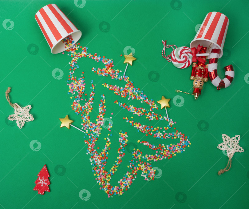 Скачать Рождественский фон. Сахарные звездочки в форме рождественской елки разбросаны по зеленому фону вместе с елочными украшениями фотосток Ozero