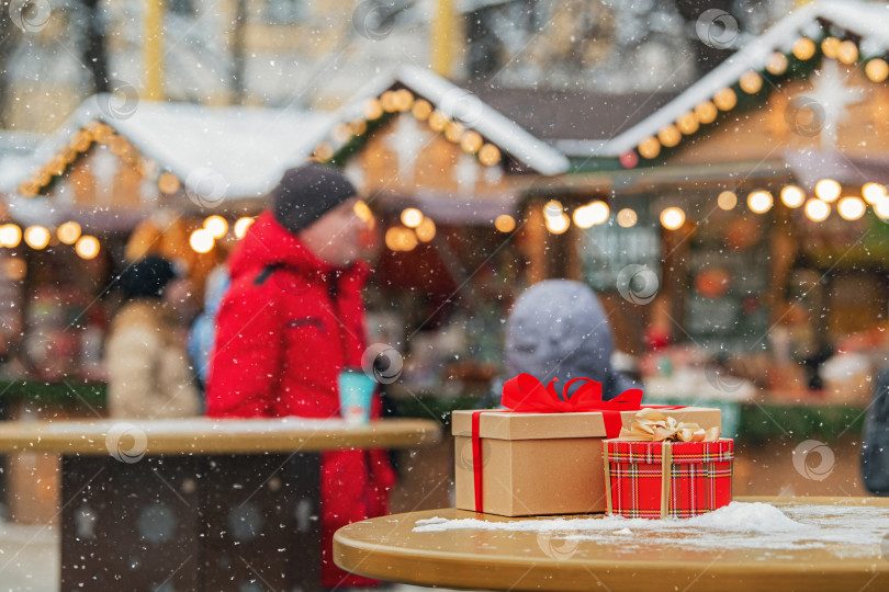 Скачать Подарочная коробка на праздничном столе с падающим снегом. Рождественская ярмарка фотосток Ozero