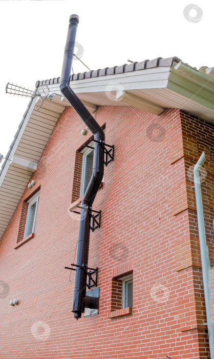 Скачать Кирпичная стена дома с дымоходной системой из темного металла и белыми оконными рамами. Детали жилой архитектуры и строительства фотосток Ozero