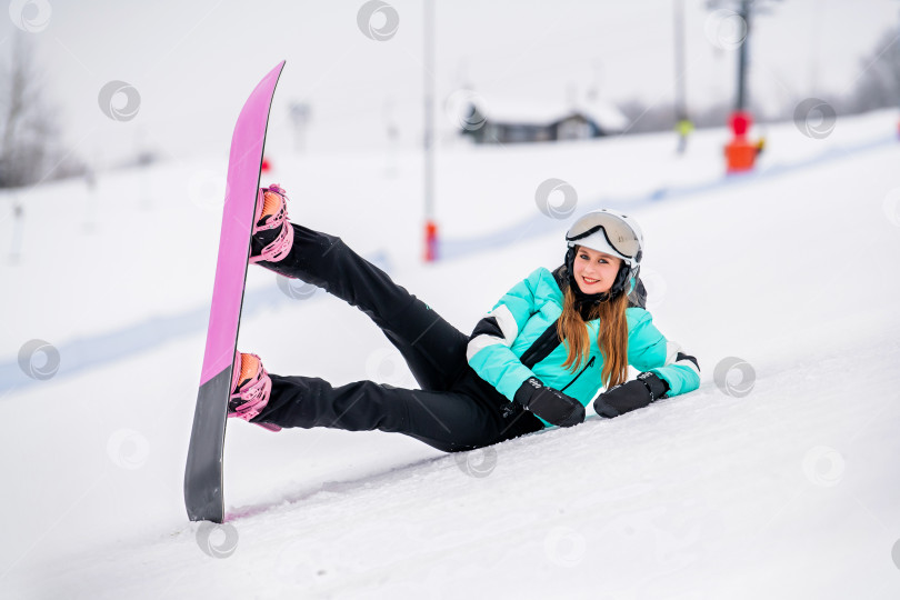 Скачать Молодая сноубордистка, скользящая по заснеженному склону в стильном зимнем снаряжении. Захватывающие зимние виды спорта. фотосток Ozero
