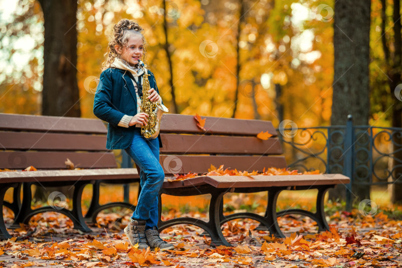 Скачать Молодая девушка играет на саксофоне в осеннем парке. фотосток Ozero