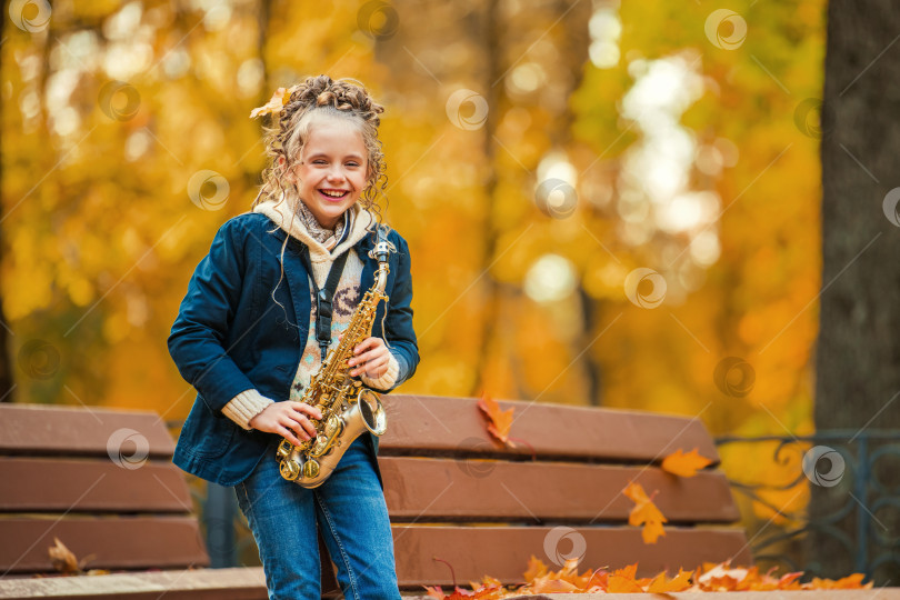 Скачать Счастливая молодая женщина играет на саксофоне на открытом воздухе прекрасным осенним днем. фотосток Ozero
