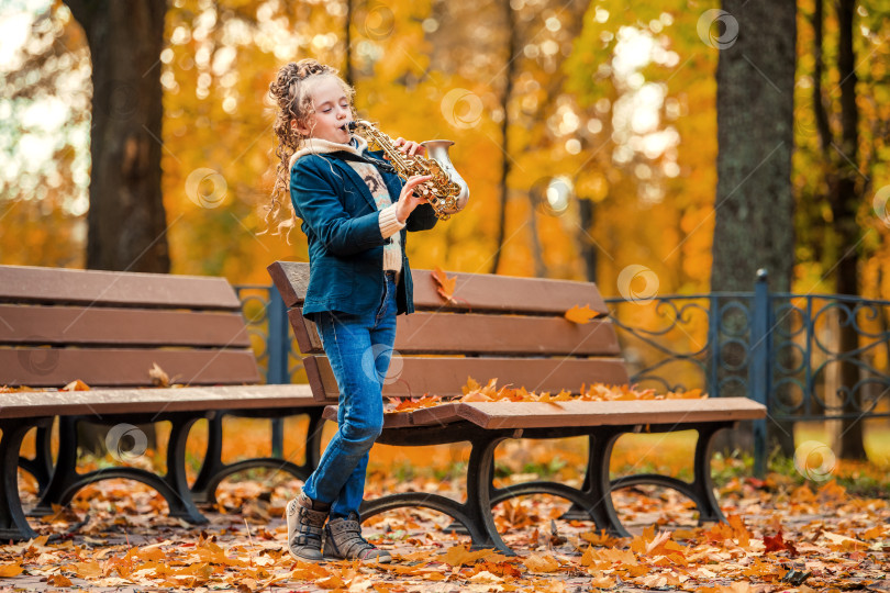 Скачать Молодая девушка играет на саксофоне в осеннем парке. фотосток Ozero