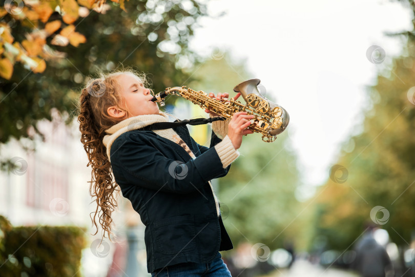 Скачать Молодая девушка играет на саксофоне во время выступления на открытом воздухе. фотосток Ozero