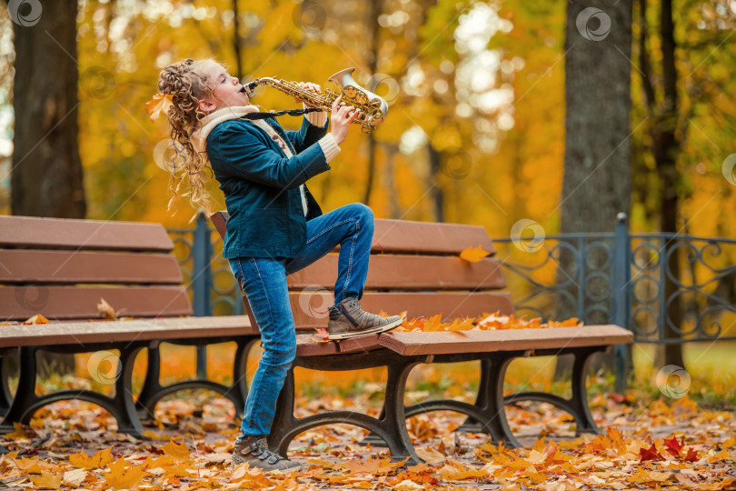Скачать Молодая девушка играет на саксофоне в осеннем парке. фотосток Ozero