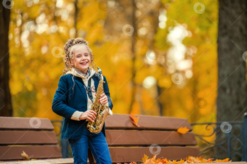 Скачать Счастливая молодая женщина играет на саксофоне на открытом воздухе прекрасным осенним днем. фотосток Ozero
