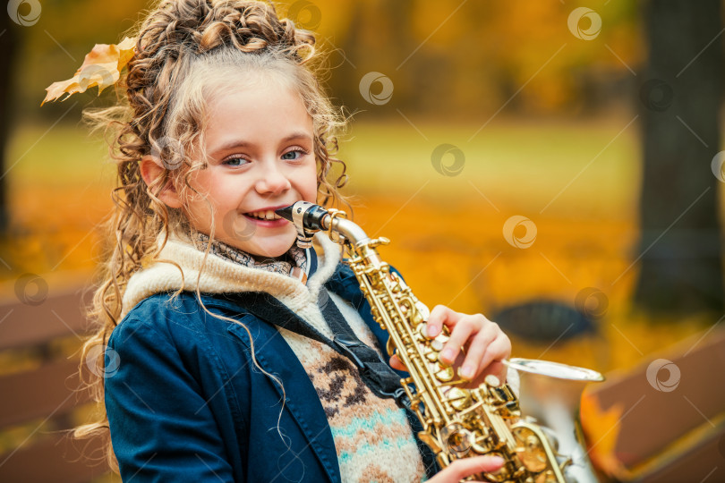 Скачать Счастливая молодая девушка, играющая на саксофоне на открытом воздухе прекрасным осенним днем. фотосток Ozero