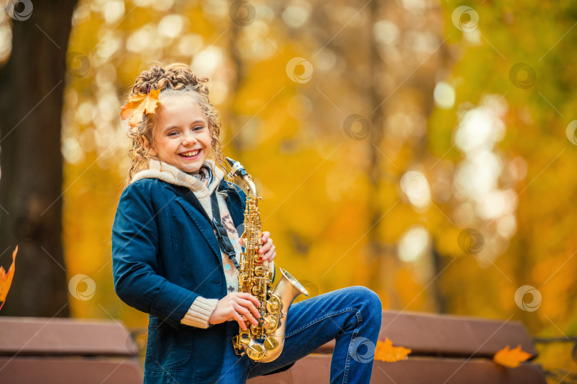 Скачать Счастливая молодая женщина играет на саксофоне на открытом воздухе прекрасным осенним днем. фотосток Ozero