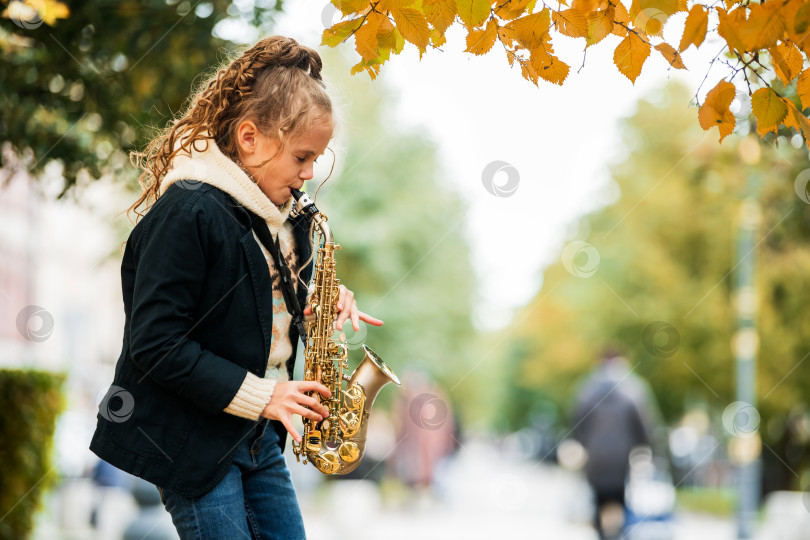 Скачать Молодая девушка играет на саксофоне во время выступления на открытом воздухе. фотосток Ozero