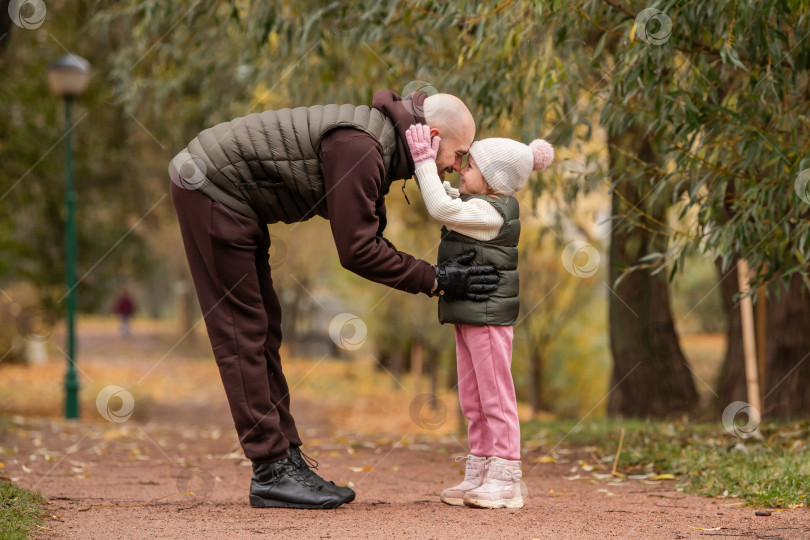 Скачать Маленькая дочь обнимает своего любящего отца во время прогулки по осеннему парку. фотосток Ozero