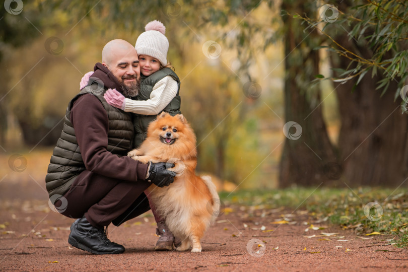 Скачать Маленькая дочь обнимает своего любящего отца во время прогулки по осеннему парку. фотосток Ozero