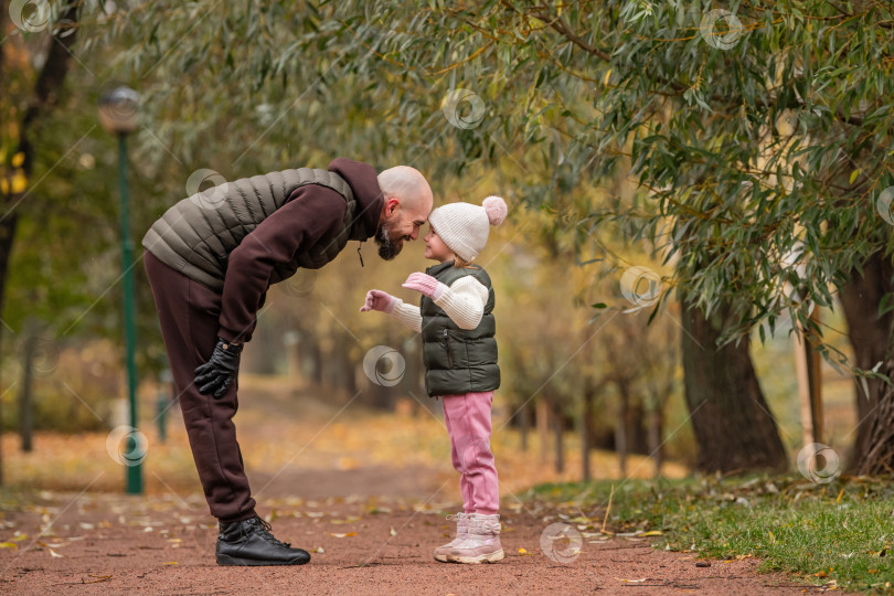 Скачать Маленькая дочь обнимает своего любящего отца во время прогулки по осеннему парку. фотосток Ozero