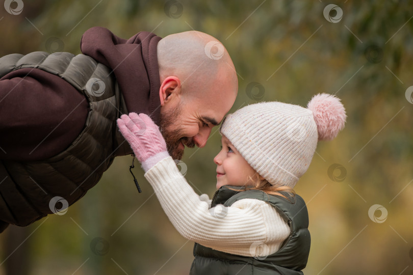 Скачать Маленькая дочь обнимает своего любящего отца во время прогулки по осеннему парку. фотосток Ozero