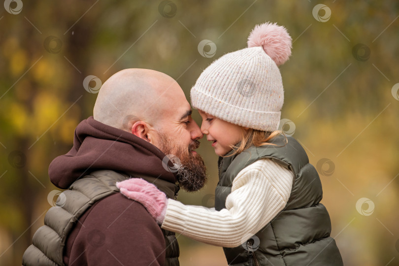 Скачать Маленькая дочь обнимает своего любящего отца во время прогулки по осеннему парку. фотосток Ozero