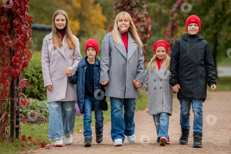 Скачать Женщина и дети гуляют в парке, держась за руки. Счастливая семья в осенний период, когда опадает листва. фотосток Ozero