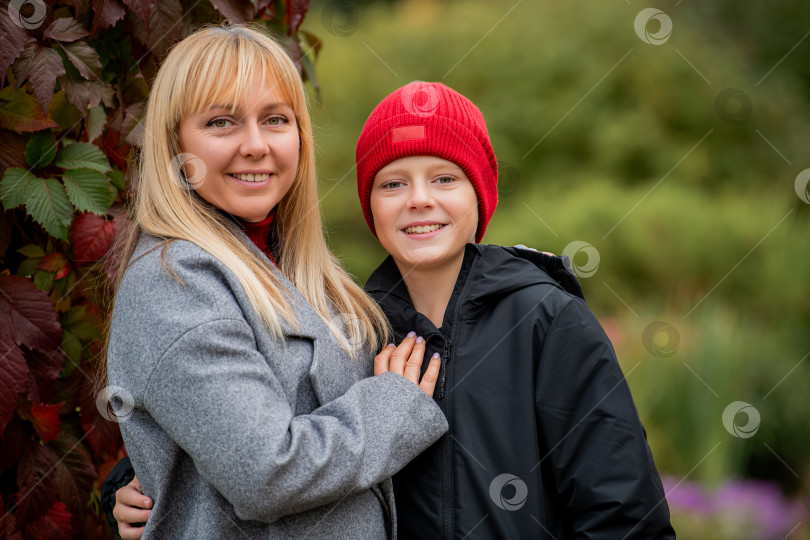 Скачать Мать и мальчик стоят рядом, улыбаясь в камеру на улице. фотосток Ozero