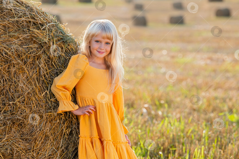 Скачать Молодая девушка в желтом платье отдыхает у тюка сена фотосток Ozero