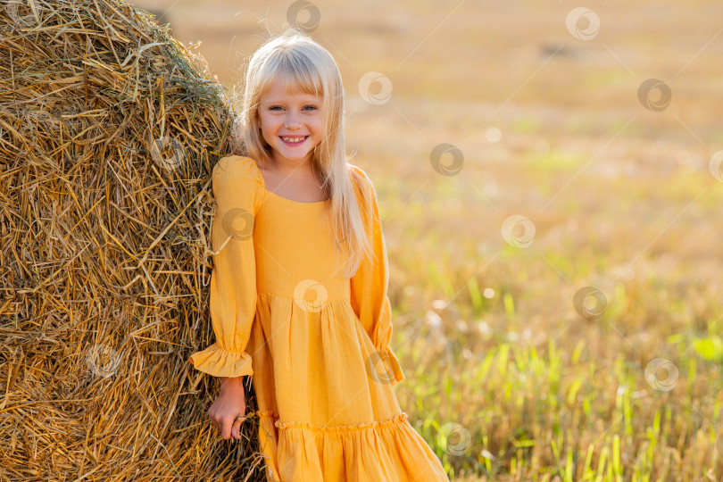 Скачать Молодая девушка в желтом платье отдыхает у тюка сена фотосток Ozero