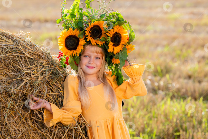 Скачать Улыбающийся ребенок с короной из подсолнухов на солнечном поле фотосток Ozero