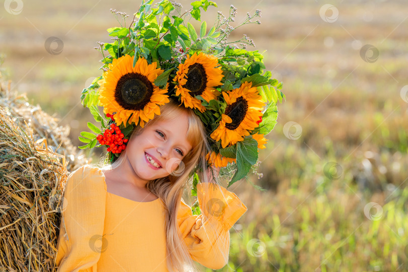 Скачать Улыбающийся ребенок с короной из подсолнухов на солнечном поле фотосток Ozero
