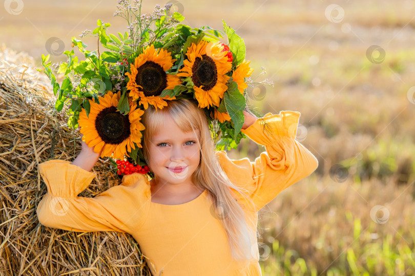 Скачать Улыбающийся ребенок с короной из подсолнухов на солнечном поле фотосток Ozero