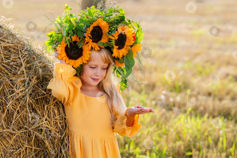 Скачать Улыбающийся ребенок с короной из подсолнухов на солнечном поле фотосток Ozero