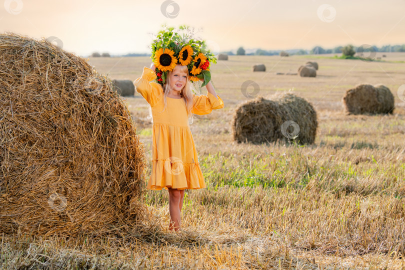 Скачать Улыбающийся ребенок с короной из подсолнухов на солнечном поле фотосток Ozero