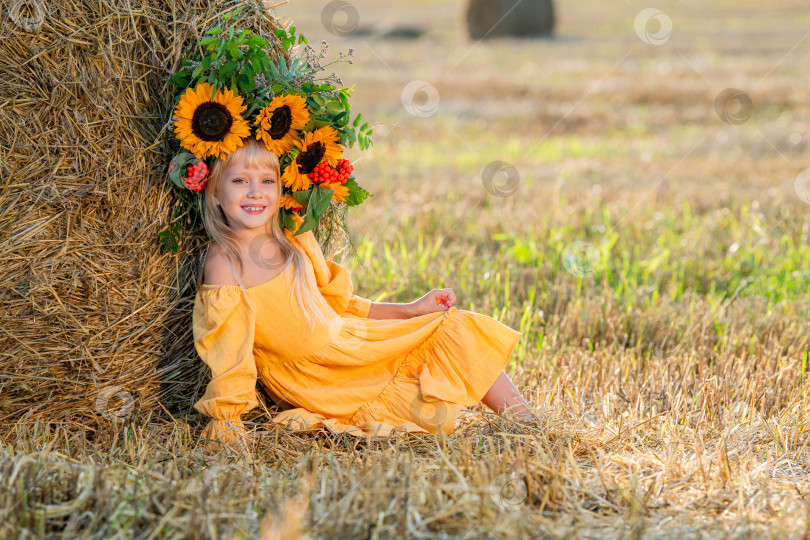 Скачать Улыбающийся ребенок с короной из подсолнухов на солнечном поле фотосток Ozero