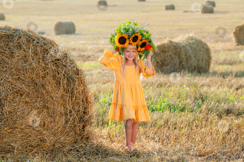 Скачать Улыбающийся ребенок с короной из подсолнухов на солнечном поле фотосток Ozero