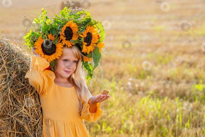 Скачать Улыбающийся ребенок с короной из подсолнухов на солнечном поле фотосток Ozero