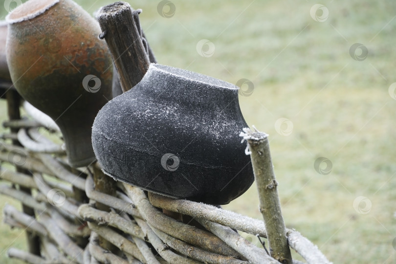 Скачать Чугунный котелок и прочая кухонная утварь на сельском плетне. Деревенское домашнее хозяйство. фотосток Ozero