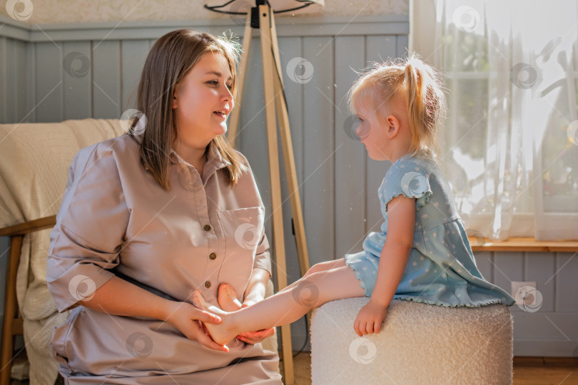 Скачать Мать играет со своей маленькой дочкой и щекочет ее босые ножки. фотосток Ozero