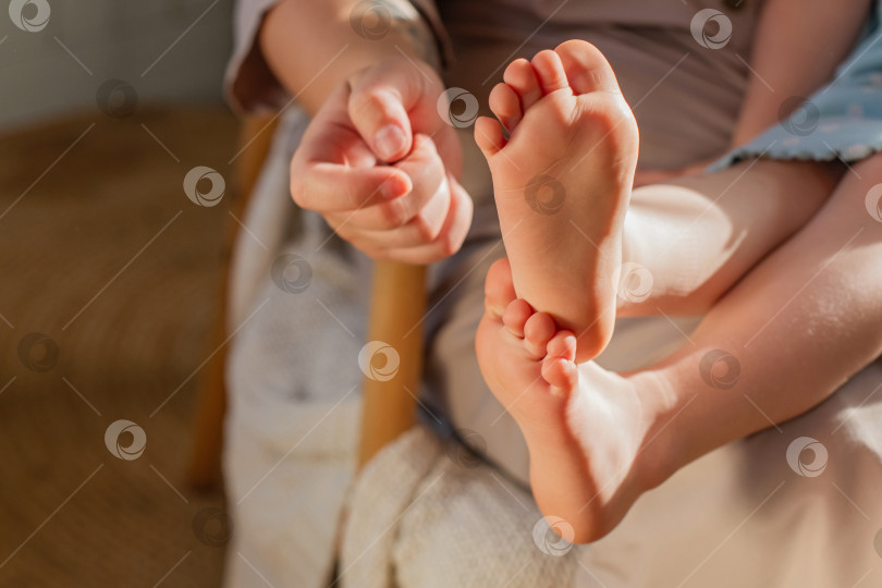 Скачать Детские ножки крупным планом. Рука матери щекочет пятки. фотосток Ozero