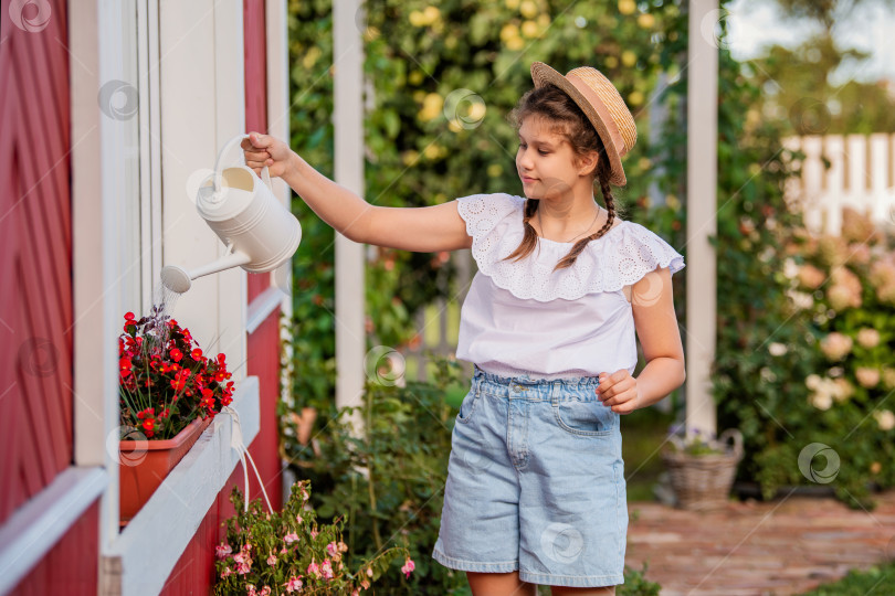 Скачать Девушка поливает цветы из лейки в саду фотосток Ozero