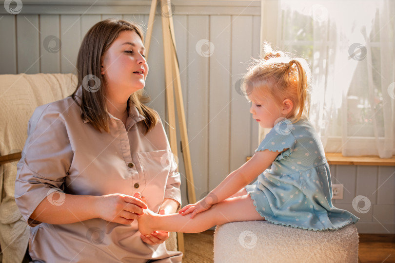 Скачать Мать играет со своей маленькой дочкой и щекочет ее босые ножки. фотосток Ozero