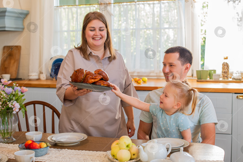 Скачать Семья наслаждается совместным завтраком на уютной кухне фотосток Ozero