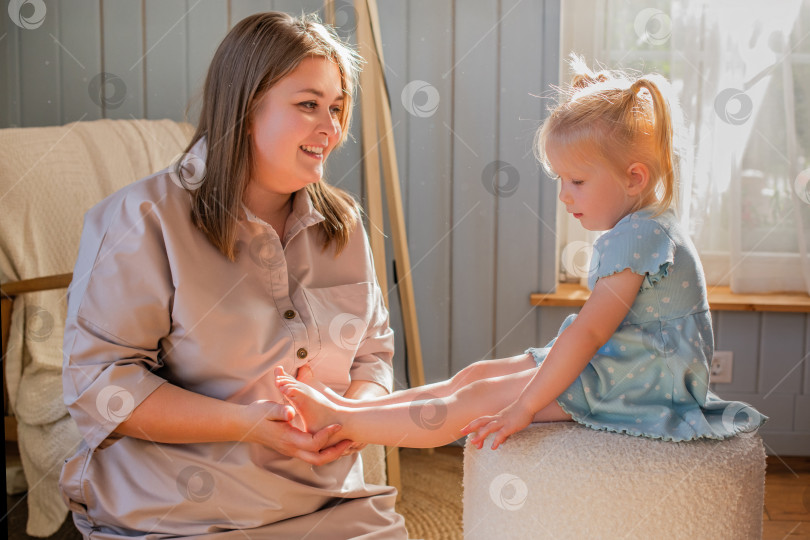 Скачать Мать играет со своей маленькой дочкой и щекочет ее босые ножки. фотосток Ozero