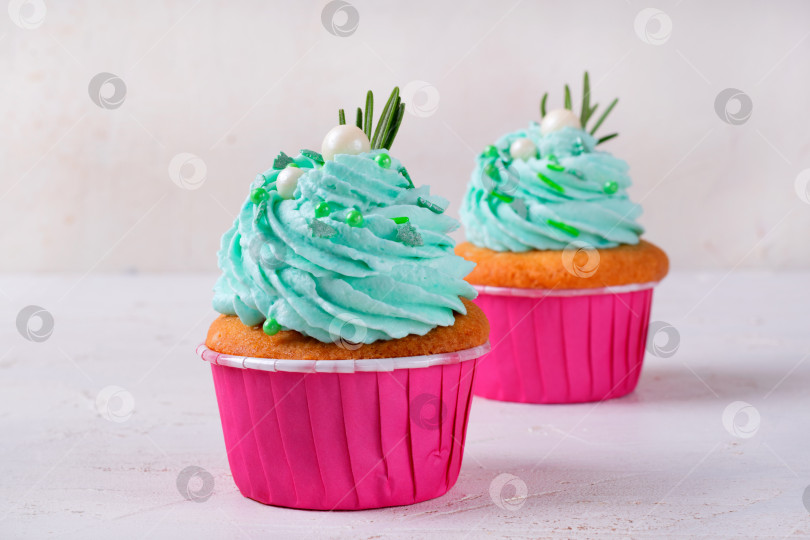 Скачать Рождественские кексы с зеленой глазурью, украшенные сахарной пудрой и розмарином, в розовой чашечке фотосток Ozero