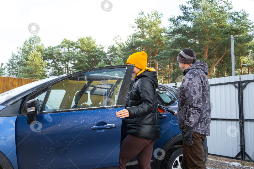 Скачать Женщина садится за руль, муж и жена садятся в машину возле дома во дворе фотосток Ozero