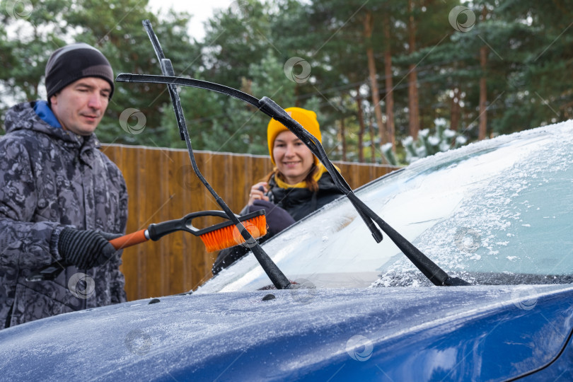 Скачать Муж и жена очищают машину ото льда возле дома во дворе в осенние морозы фотосток Ozero