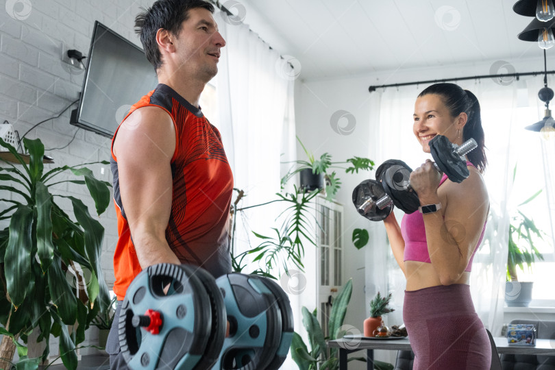 Скачать Совместная силовая тренировка мужа и жены дома с гантелями фотосток Ozero