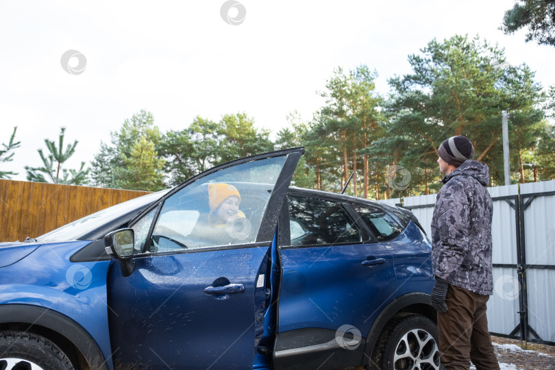 Скачать Женщина садится за руль, муж и жена садятся в машину возле дома во дворе фотосток Ozero