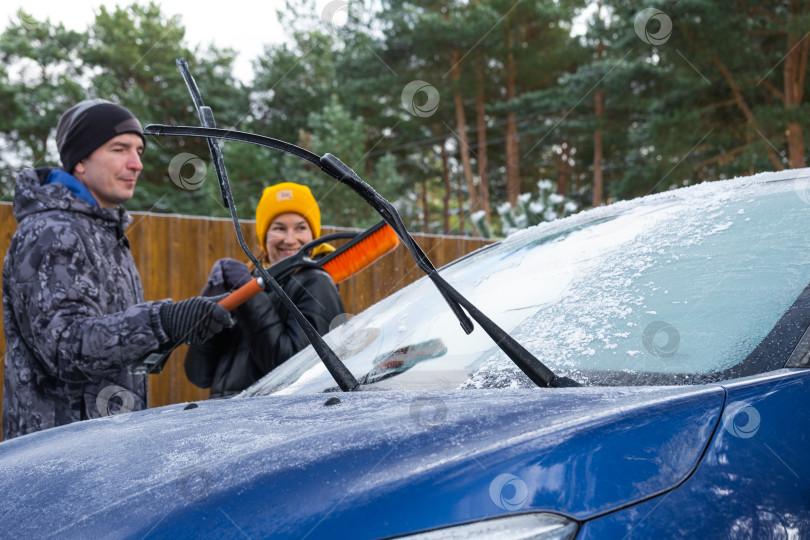 Скачать Муж и жена очищают машину ото льда возле дома во дворе в осенние морозы фотосток Ozero