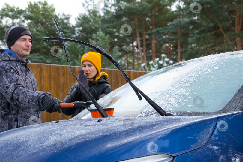 Скачать Муж и жена очищают машину ото льда возле дома во дворе в осенние морозы фотосток Ozero